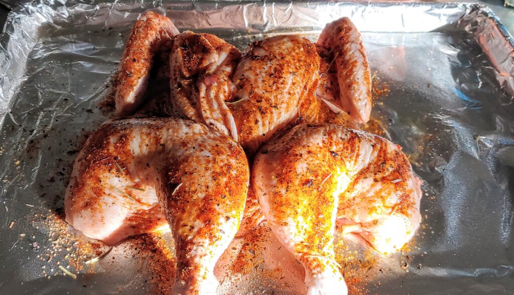 A chicken spatchcocked and laying on a pan.